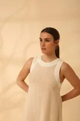 Vestido corto color beige claro, sin mangas y de corte recto. Confeccionado en lino.