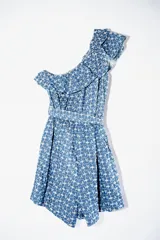 Mono corto azul con estampado de flores blancas, un hombro descubierto con volantes y cintura elástica.