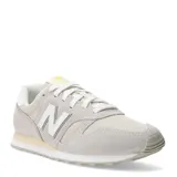 Championes urbanos New Balance modelo 373 para mujer, color gris claro/beige con detalles en blanco y cordones blancos. Presentan una combinación de gamuza y malla en el exterior.