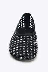 Zapato tipo bailarina color negro, con acabado en punta redonda y suela plana. Diseño de rejilla con tachas plateadas en todo el cuerpo.