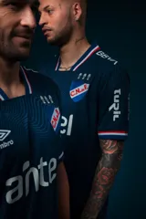 Camiseta de fútbol Umbro del Club Nacional de Football, modelo Alternativa. Diseño azul con detalles en blanco y rojo en cuello y mangas. Incluye logo de Umbro, escudo del club y sponsor Antel en el frente.