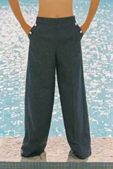 Pantalón ancho azul de tiro alto confeccionado en lino, con bolsillos delanteros con falsos botones y cierre lateral con cremallera oculta.