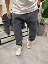 Pantalón de jogging gris lavado con puños elásticos, bolsillos laterales tipo cargo y bolsillos traseros.