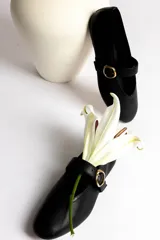 Ballerinas negras de cuero con tira sobre el empeine y hebilla dorada.