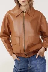 Campera bomber de cuero color marrón con cierre frontal, cuello clásico, bolsillos plaqué con tapa y puños y cintura acanalados.