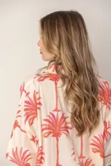 Camisa color crema con estampado de palmeras rosas, de corte recto y manga corta.