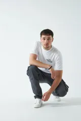 Pantalón cargo color beige, con cintura elástica ajustable con cordón, bolsillos laterales con cierre y bolsillos cargo con solapa.