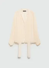 Blusa color crema de mangas largas abullonadas, con lazo en el cuello y tejido semitransparente.