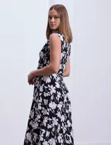 Vestido largo sin mangas, con escote en V cruzado y estampado floral en blanco sobre fondo negro.