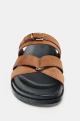 Sandalia plana de serraje color marrón, con dos tiras cruzadas en la parte delantera y una tira ancha con hebilla metálica ajustable.