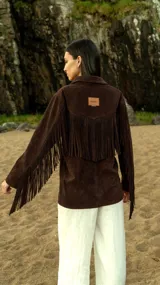 Blazer marrón de gamuza ligera con flecos largos en las mangas y botones de cuerno. Corte recto y bolsillos frontales.