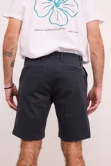 Bermuda de gabardina color verde oliva, con bolsillos laterales y traseros. Cierre frontal con botón y cremallera.