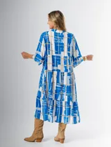 Vestido midi de corte amplio con estampado abstracto en tonos azules, blancos y beige. Tiene cuello en V, mangas 3/4 con volados y corte escalonado en la falda.