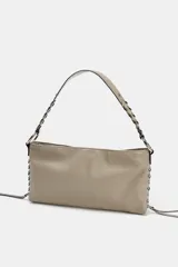 Bolso de hombro color gris topo, con formato rectangular y asa corta. Presenta dos bolsillos frontales con cierre de cremallera y detalle de tiras colgantes. El asa es de cuero trenzado con herrajes metálicos.