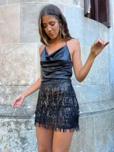 Minifalda negra de lentejuelas con flecos en el ruedo y tirantes finos con strass.