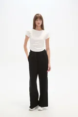 Pantalón deportivo negro de corte holgado, con cintura elástica, bolsillos laterales y botones a presión en las costuras laterales de las piernas.