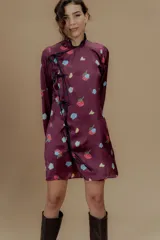 Vestido corto color borgoña con estampado de rosas y limones, mangas largas, cuello mao y cierre lateral con lazos negros.