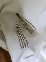 Aros colgantes plateados con forma de líneas onduladas.