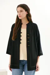 Sobrecamisa beige de corte recto, cuello mao y mangas 3/4. Presenta cierre frontal con botones de madera y bolsillos laterales.