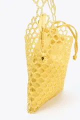 Bolso mini tipo saco con cuerpo de abalorios amarillos, asa de hombro de cuentas y asa bandolera de cadena. Incluye bolsita interior con cierre fruncido.