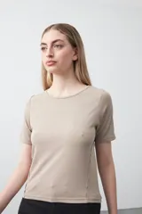 Remera de manga corta color beige claro, confeccionada en tejido acanalado elástico, con cuello redondo.