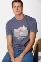 Remera gris de manga corta con cuello redondo y estampado de paisaje de montaña con osos y pinos. Incluye el texto "legacy brand get elevated".