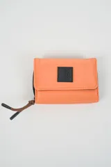 Billetera plegable color naranja con cierre de velcro y detalle de cordón marrón en el lateral. Presenta un parche negro con texto en relieve en la solapa frontal.