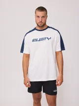 Remera blanca de algodón con mangas cortas y corte en hombro/manga color azul marino. Estampado frontal con el logo de la marca en azul y gris.