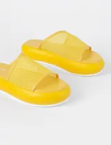 Sandalia asimétrica calada color amarillo, con parte superior de PVC y suela de goma.