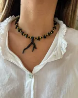 Collar con piedras negras y detalles en dorado, ajuste regulable en la parte posterior.