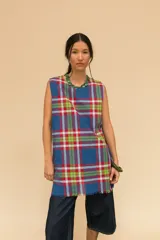 Vestido corto sin mangas con estampado de cuadros tartán en tonos azul, rojo, verde y blanco. Tiene cuello redondo y ruedo con flecos.