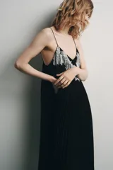 Vestido midi negro de tejido plisado, con escote pico, tirantes finos ajustables y aplicación de encaje y bordados florales combinados a contraste.