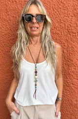 Colgante largo con cordón marrón y cuentas de diversos colores y formas. Incluye un dije central metálico con diseño de nudo celta y terminaciones de cordón sueltas.