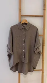 Camisa marrón de lino con botones blancos, corte holgado y mangas cortas.