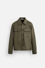 Sobrecamisa color verde oliva de corte recto, confeccionada en tejido efecto ante. Tiene cuello solapa, manga larga con puños abotonados, bolsillos de plastrón con solapa en el pecho y bolsillos de vivo en la cadera. Cierre frontal con botones.