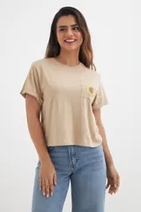 Remera color beige de algodón con bolsillo en el pecho y estampado de girasol.