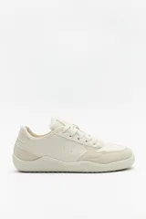 Zapatillas de cuero color blanco y beige, de diseño minimalista con suela marrón.