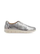 Sneaker de cuero blanco con talón dorado, cordones finos y suela beige con diseño anatómico.