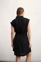 Vestido camisero corto color beige, con cuello clásico, mangas cortas con puños, dos bolsillos con solapa en el pecho, cinturón de lazo y cierre frontal con botones.