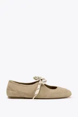 Zapato plano tipo bailarina color beige, de serraje, con puntera redondeada, suela plana y cierre con cordones.