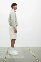 Short cargo color crema en popelina de algodón, con cintura elástica ajustable con cordón, bolsillos laterales y bolsillos con solapa y botones a presión en las piernas y atrás.