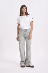 Pantalón de jean celeste de corte ancho, con detalles de ojalillos metálicos en la parte delantera.