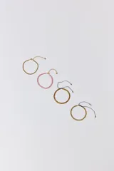 Set de cuatro pulseras: una dorada de cadena, una rosa de cuentas, una dorada tejida con cordón negro ajustable y una dorada con textura y cordón negro ajustable.
