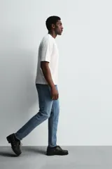 Pantalón de jean negro, corte slim fit, con tiro medio, cinco bolsillos, efecto lavado y cierre frontal con cremallera y botón.