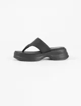 Sandalia negra de plataforma gruesa, estilo ojota o chancla, con tira ancha que sujeta el empeine y separación para el dedo gordo.