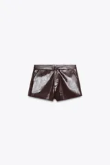 Shorts de tiro alto color marrón chocolate con efecto cuero. Presentan bolsillos laterales y falsos bolsillos de vivo en la espalda. Cierre frontal con cremallera y gancho metálico.