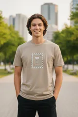 Remera de manga corta color beige con cuello redondo. Presenta un estampado central que simula una estampilla italiana con una columna clásica y la palabra "ITALIA" en la parte inferior.