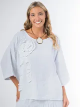 Remera oversized confeccionada en lino italiano color blanco, con aplique tridimensional de flor en el mismo lino.