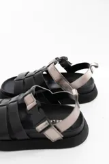 Sandalias negras de cuero con tiras horizontales y hebilla plateada.