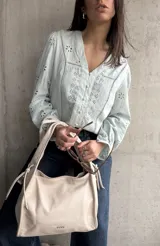 Camisa celeste con bordados florales, cuello en V y cierre frontal con botones.